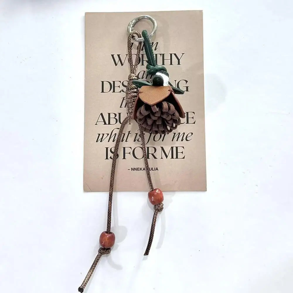 Breloque de sac à main avec pompon fleuri pour femme, porte-clés haut de gamme en cuir PU, pendentif en corde tressée avec pomme de pin et fleur.