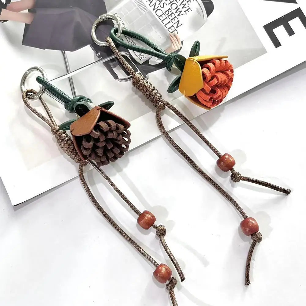 Breloque de sac à main avec pompon fleuri pour femme, porte-clés haut de gamme en cuir PU, pendentif en corde tressée avec pomme de pin et fleur.